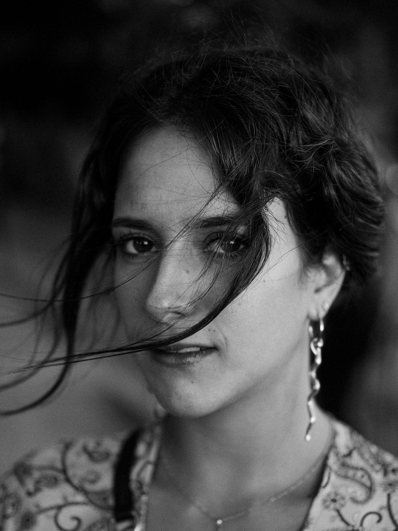 Black and white portrait of a woman with wind in her dark hair, long earrings