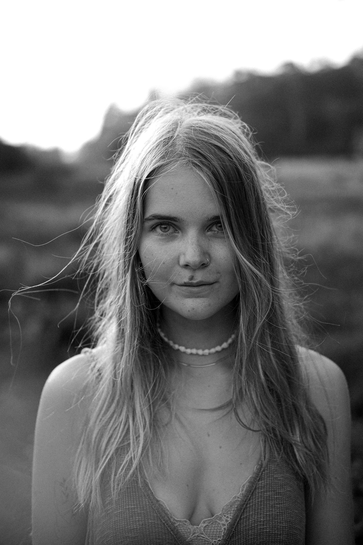 Black and white portrait of a young woman with long hair and a shell necklace