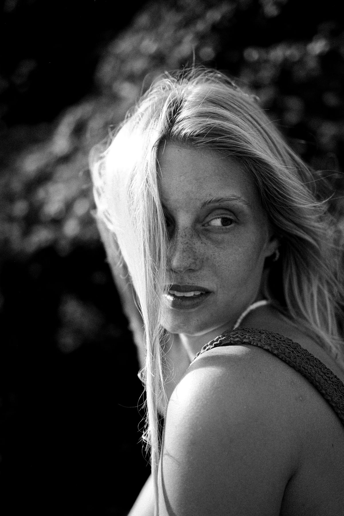 Black and white portrait of a woman looking back over her shoulder, hair across her face