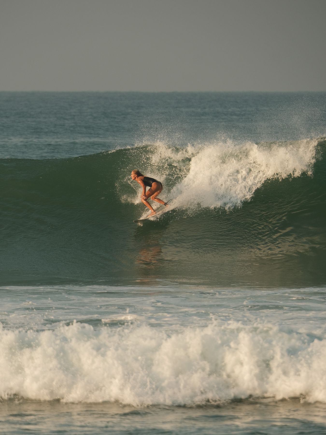 Surfer riding down the face of a breaking wave