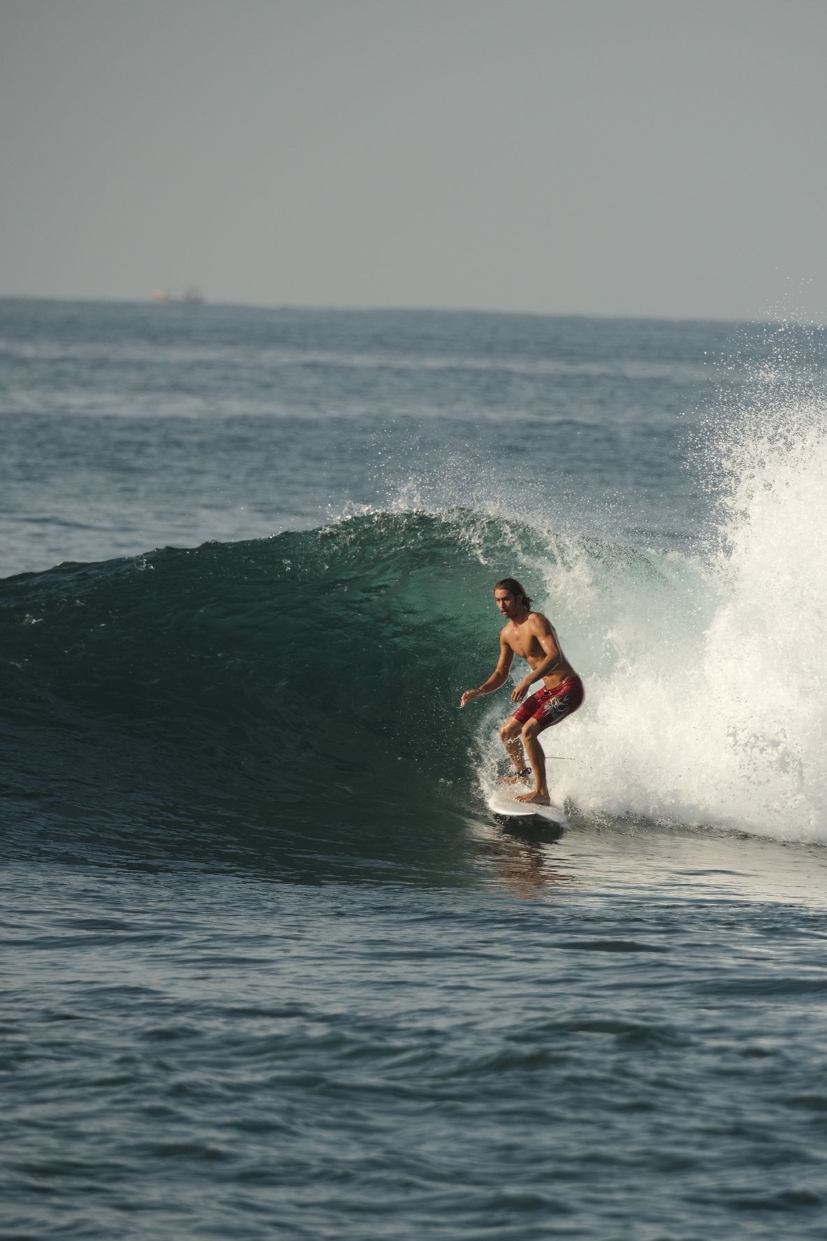 Surfer in red shorts riding inside a green wave