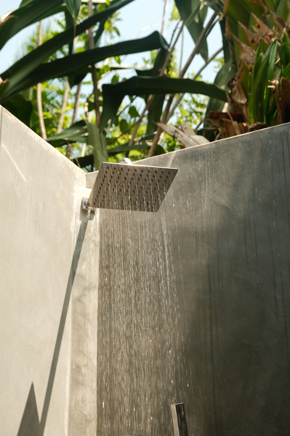 Outdoor rain shower between concrete walls and tropical plants
