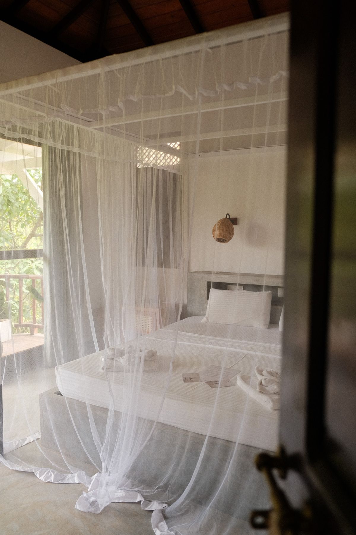 Four-poster bed with a white mosquito net in a villa bedroom