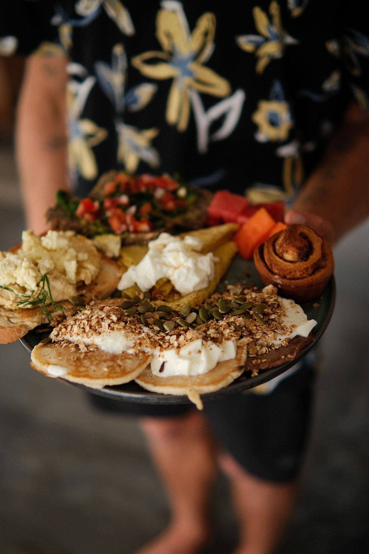 Breakfast platter with pancakes, fruit and nuts carried to the table